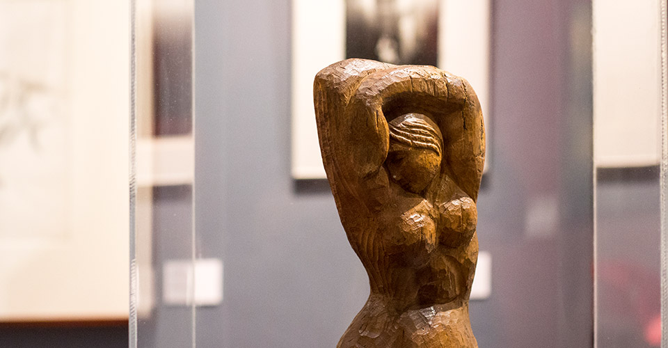 Detalle de una escultura en madera de una mujer con los brazos abrazando la cabeza del artista Juan Manuel Sánchez